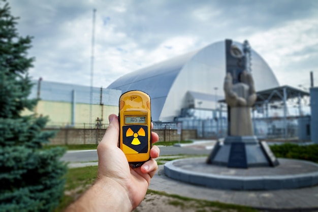 Un dosímetro en manos con un nivel de radiactividad cerca del monumento a los liquidadores de Chernobyl cerca del cuarto reactor. Historia del desastre de Chernobyl. Lugar perdido en Ucrania, URSS