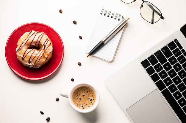 Doughnouts auf einem Schreibtisch-Station-Büro. Pausenkonzept