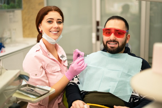 Doutor e paciente fêmeas novos do dentista que sorriem na câmera na clínica dental.