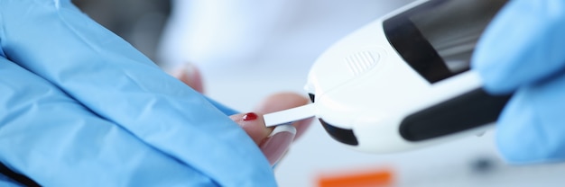 Doutor em luvas faz teste de açúcar no sangue em paciente com conceito de sintomas de diabetes com glicosímetro
