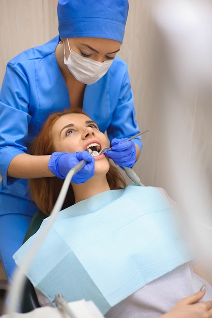 Doutor em uniforme, verificando os dentes do paciente do sexo feminino na clínica odontológica