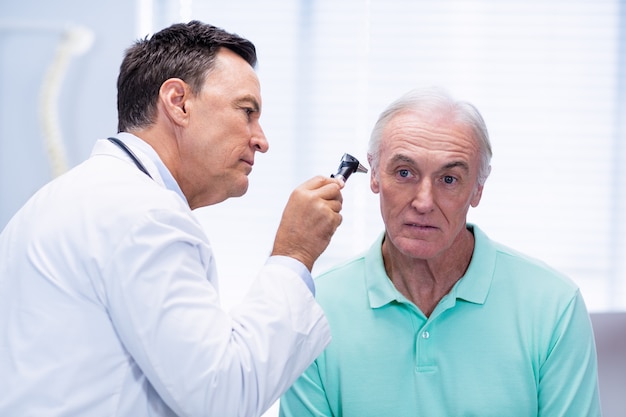 Foto doutor examinando pacientes ouvido com otoscópio