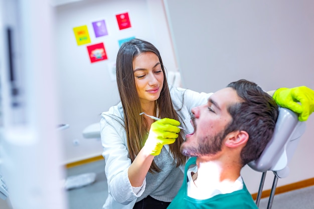 Doutor fazendo tratamento odontológico nos dentes do homem na cadeira de dentista.