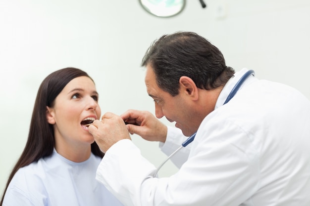 Doutor olhando a boca de seu paciente