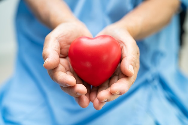 Doutor que guarda um coração vermelho no conceito médico forte saudável do hospital