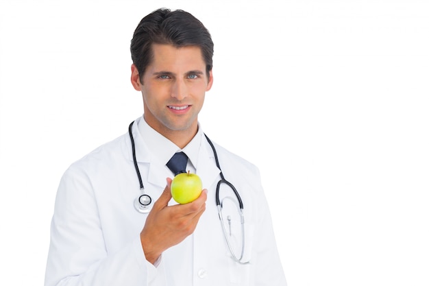 Doutor, segurando uma maçã e sorrindo para a câmera em um fundo branco