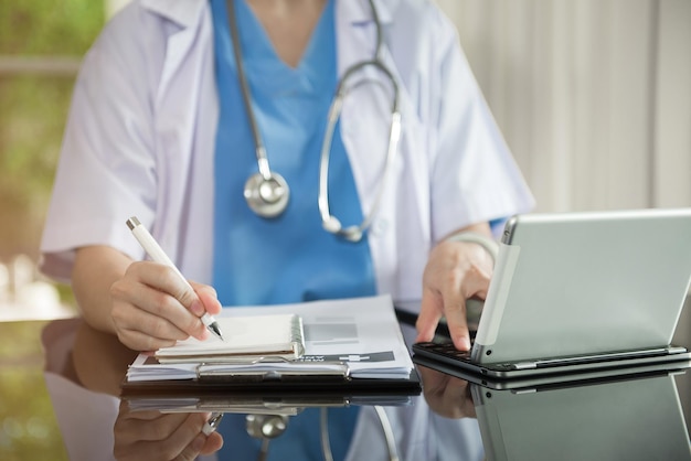 Foto doutor sentado à mesa e escrevendo um relatório de documento no escritório do hospital