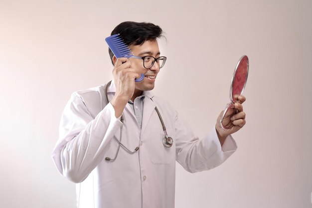 Foto doutor sorridente penteando o cabelo enquanto está de pé contra um fundo branco