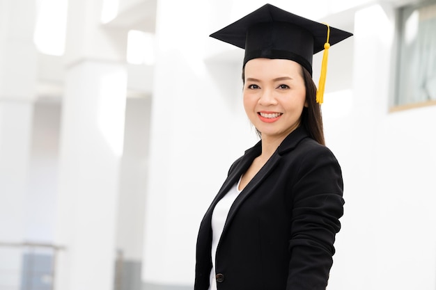 Doutorandos do sexo feminino usando bonés de formatura de borla amarela preta estão na universidade.