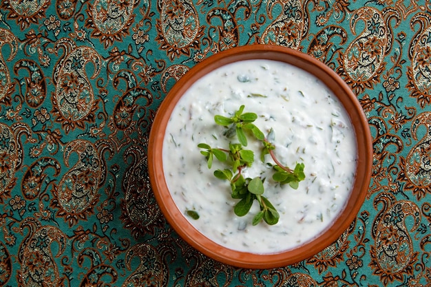 Dovga na placa de madeira comida nacional do azerbaijão sopa cremosa dovga sopa dovga azerbaijana com verdes em uma tigela branca