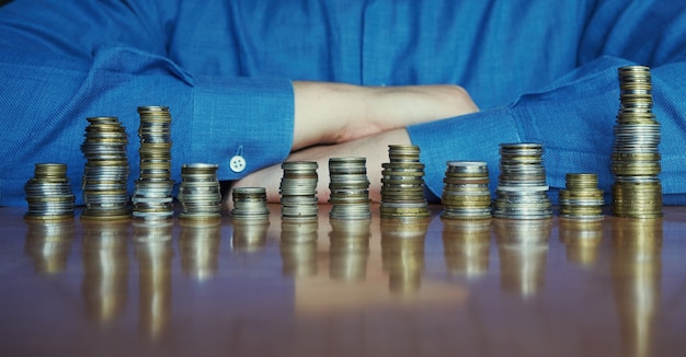 Doze pilhas de moedas em uma mesa com o homem de camisa azul no fundo. análise anual do conceito de vendas sazonais