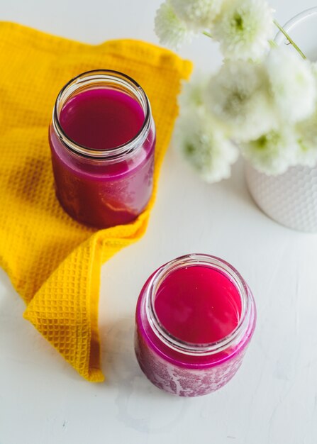 Drachenfruchtsaft in einem Glas, gelbe Serviette, einige Pflanzen.