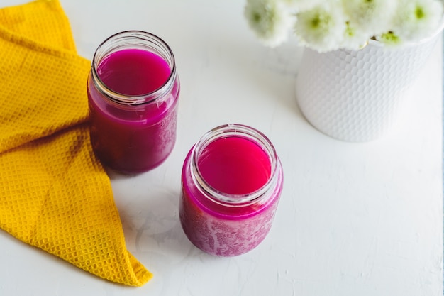 Drachenfruchtsaft in einem Glas, gelbe Serviette, einige Pflanzen.