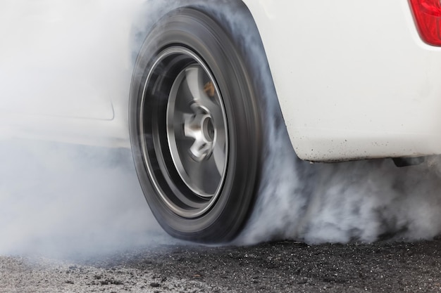 Drag racing car quema goma de sus neumáticos en preparación para la carrera