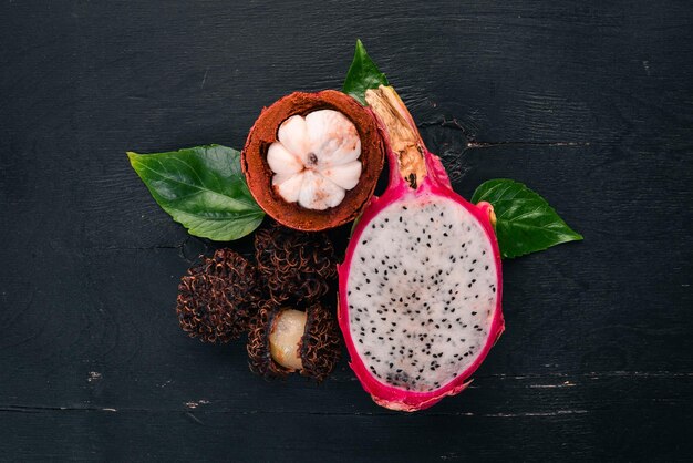 Dragon fruit rambutan y mangostán Frutas tropicales frescas Sobre un fondo de madera Vista superior Espacio de copia