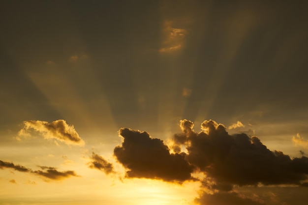 Dramática luz del sol o rayo de sol a través de las nubes en el fondo del cielo al atardecer.