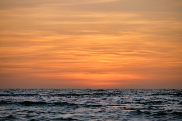 Dramáticas ondas vermelhas do oceano ao pôr-do-sol com água escura do mar suave à noite