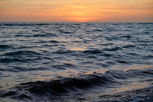 Dramatische rote Ozeanwellen bei Sonnenuntergang mit weichem dunklem Wasser am Abend