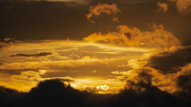 Dramatische Wolken beleuchteten den Sonnenaufgang, der am Himmel schwebt, um das Wetter zu ändern, weicher Fokus, unscharfe Bewegung