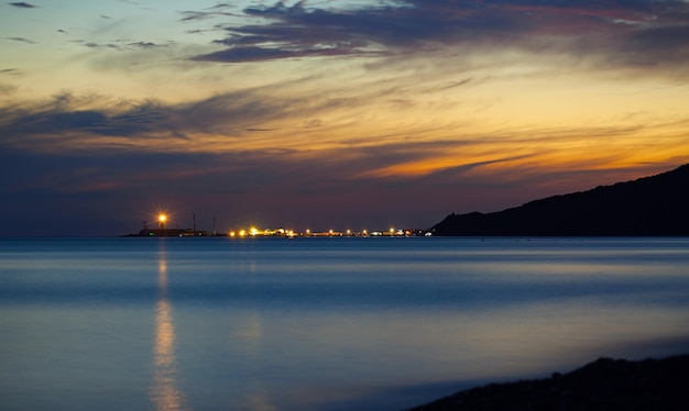 Dramatischer Sonnenuntergang an der Küste am Schwarzen Meer, Blick auf den Leuchtturm in Bolschoi Utrish, Russland