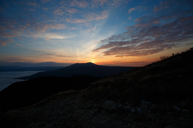 Dramatischer Sonnenuntergang Landschaft in den Herbstbergen über Wolken Schöne Skyscape mit sonnigen Balken