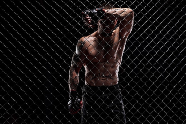 Dramatisches Bild eines Mixed-Martial-Arts-Kämpfers, der in einem achteckigen Käfig steht Das Konzept der Sportbox-Kampfkünste