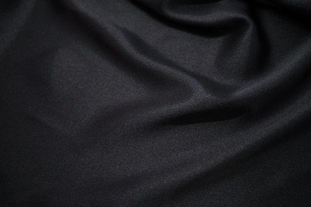 Drapeado textil de tela sedosa de satén negro abstracto con fondo de pliegues ondulados de pliegue