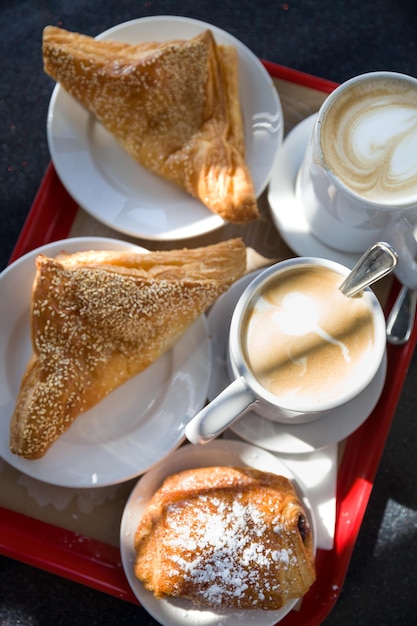 Draufsicht auf Blätterteig und Kaffeetassen auf dem Tisch im Freien Croissants und eine Tasse Kaffee