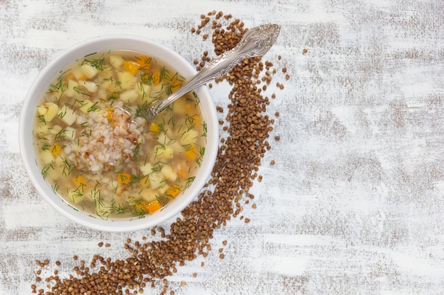 Draufsicht auf Buchweizensuppe in weißer Schüssel auf weißem Hintergrund