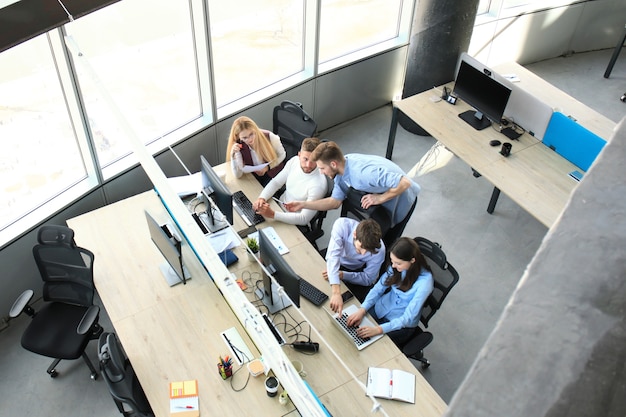 Draufsicht auf das brainstorming des geschäftsteams beim gemeinsamen sitzen am bürotisch.