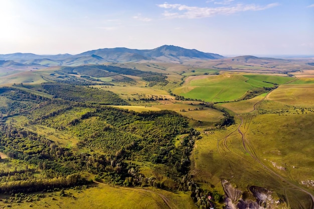 Draufsicht auf das Feld im AltaiHerbstansicht Hügeliges Gelände Gelbe Hänge und Bäume stehen im Kontrast zu grünen Feldern