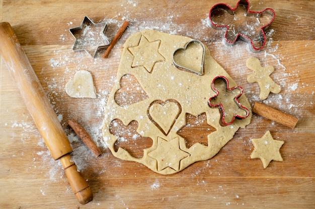 Draufsicht auf das Küchenbrett mit einem Teig für Lebkuchen mit bereits geschnittenen Formen