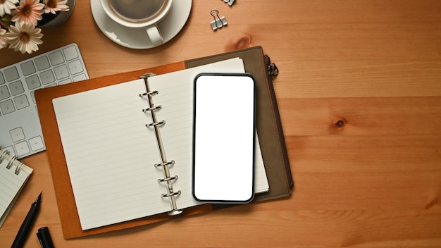 Draufsicht auf den persönlichen Organizer für Smartphones und eine Tasse Kaffee auf dem Schreibtisch aus Holz