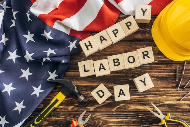 Foto draufsicht auf die amerikanische flagge und instrumente in der nähe des schutzhelms und den schriftzug „happy labor day“.