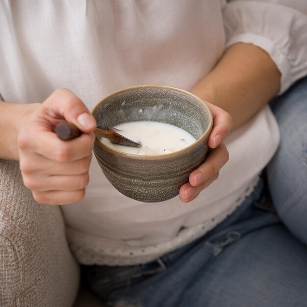 Draufsicht auf die Hände einer jungen Frau, die eine Schüssel mit hausgemachtem Bio-Vanillejoghurt mit Chiasamen halten