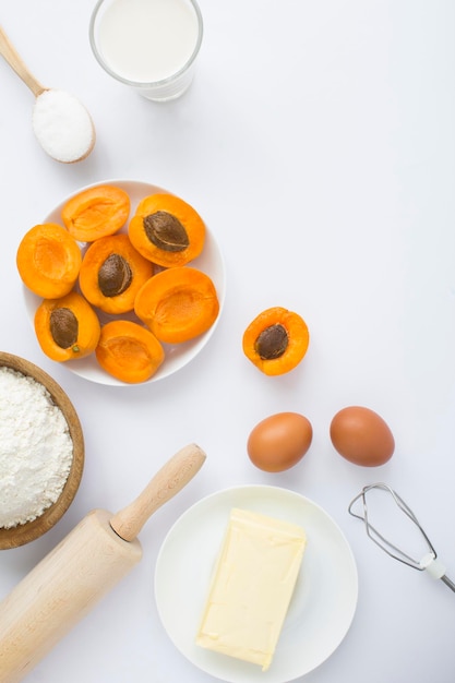 Draufsicht auf die Zutaten für die Herstellung von Aprikosenkuchen oder -kuchen auf weißem Hintergrund Kopierbereich Position vertikal