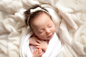 Draufsicht auf ein neugeborenes mädchen, das in einem weißen kokon auf einem weißen bett schläft schönes porträt eines kleinen mädchens 7 tage eine woche professionelle fotografie im makrostudio