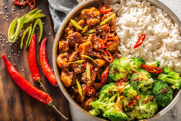 Draufsicht auf ein Teriyaki-Huhn im asiatischen Stil mit Reis, Brokkoli und Chili auf einem Vintage-Tisch.