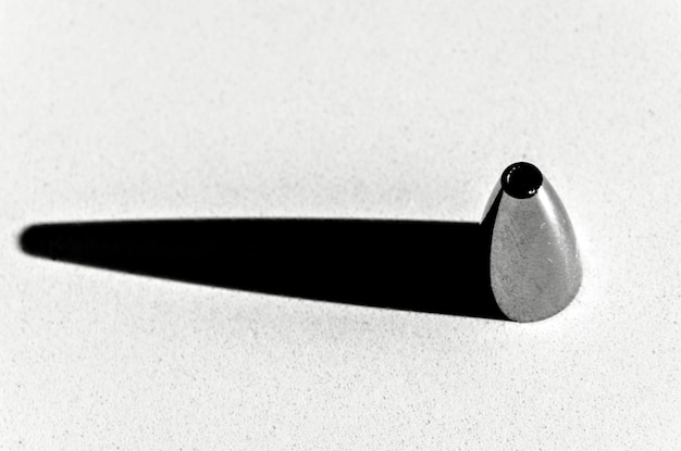 Draufsicht auf ein trichterförmiges Metall mit schwarzem horizontalem Schatten auf weißem Hintergrund.