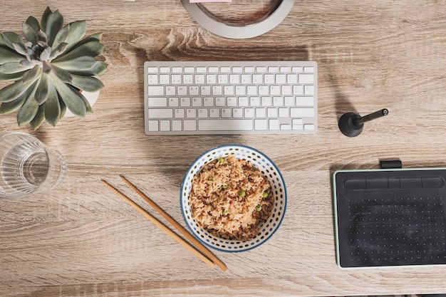 Draufsicht auf eine Schüssel mit orientalischem Reis auf dem Hintergrund des Arbeitstisches Zeit, um das Mittagessen bei der Arbeit zu genießen