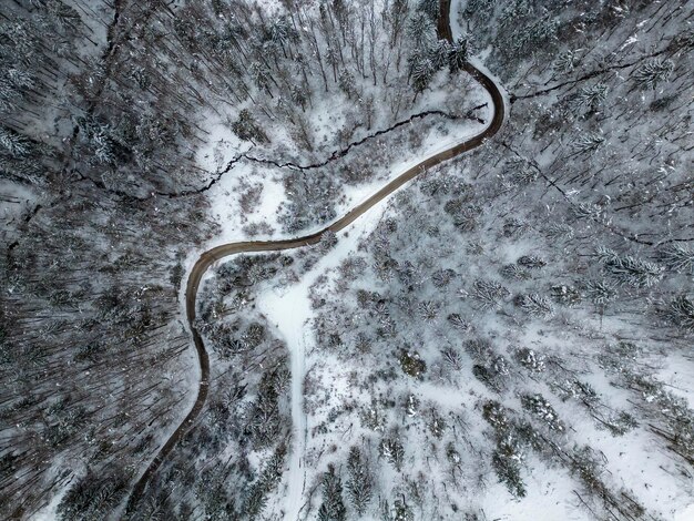 Draufsicht auf eine Straße, die durch eine schneebedeckte Winternatur führt