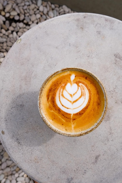 Draufsicht auf eine Tasse Cappuccino mit schöner Latte Art auf konkretem Hintergrund