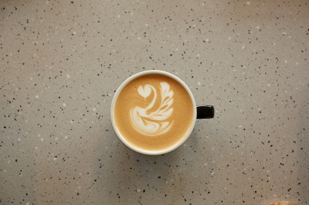 Draufsicht auf eine Tasse Kaffee mit Latte Art auf Keramiktisch im Café oder Café, Kopierraum