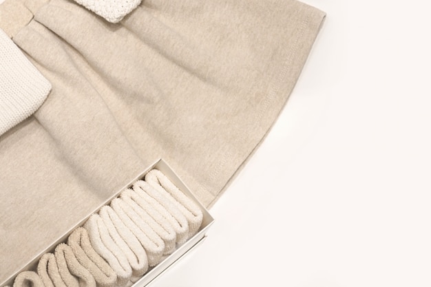 Draufsicht auf einen beigen Rock, Pullover und Socken aus natürlichen Stoffen, die auf dem Tisch liegen