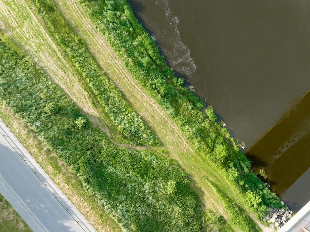 Draufsicht auf einen breiten Fluss und Grünflächen Fotografieren der Natur von einer Drohne tagsüber an einem hellen sonnigen Tag