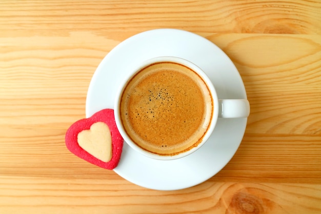 Draufsicht auf einen Espressokaffee mit herzförmigen Keksen, die auf einem Holztisch serviert werden