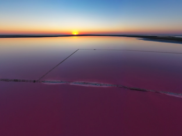 Draufsicht auf einen glänzenden salzigen rosa See und einen Weg entlang ihm