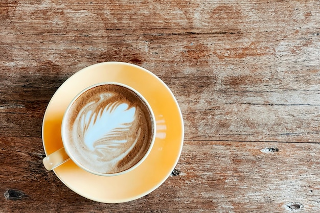 Draufsicht auf einen Latte Art Kaffee auf altem Holztisch