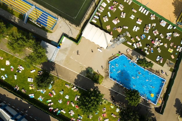 Draufsicht auf einen Ort im Freien, an dem sich Menschen entspannen können, wo es einen Swimmingpool und viele Sonnenliegen gibt