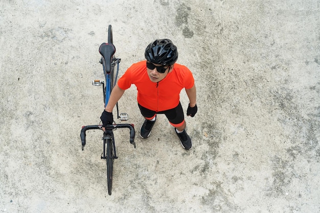 Draufsicht auf einen Radfahrer mit Helm und Sonnenbrille und einem Fahrrad im Studio isoliert auf weißem Hintergrund